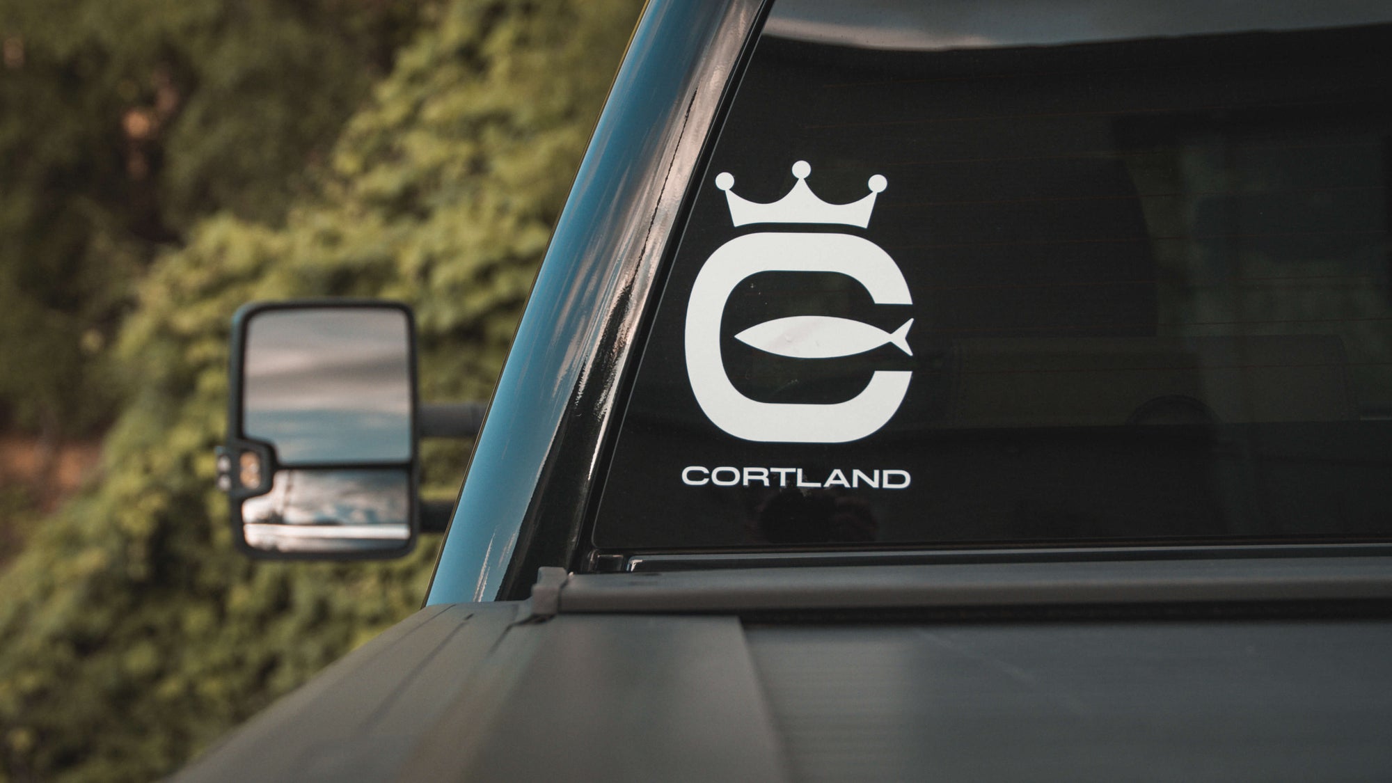 The back of a truck, with the white Cortland Logo Boat/Window Die-Cut Sticker on the back window.