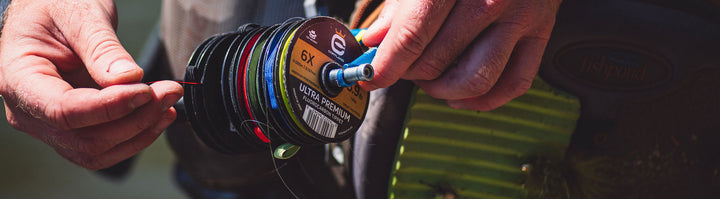 Someone holding onto a various spools of fly fishing tippet