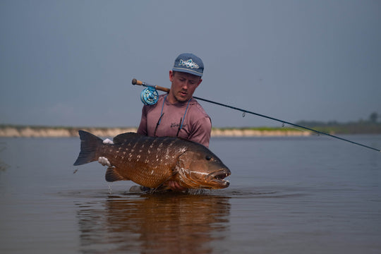 Johann du Preez standing in water holding up a brown fish 