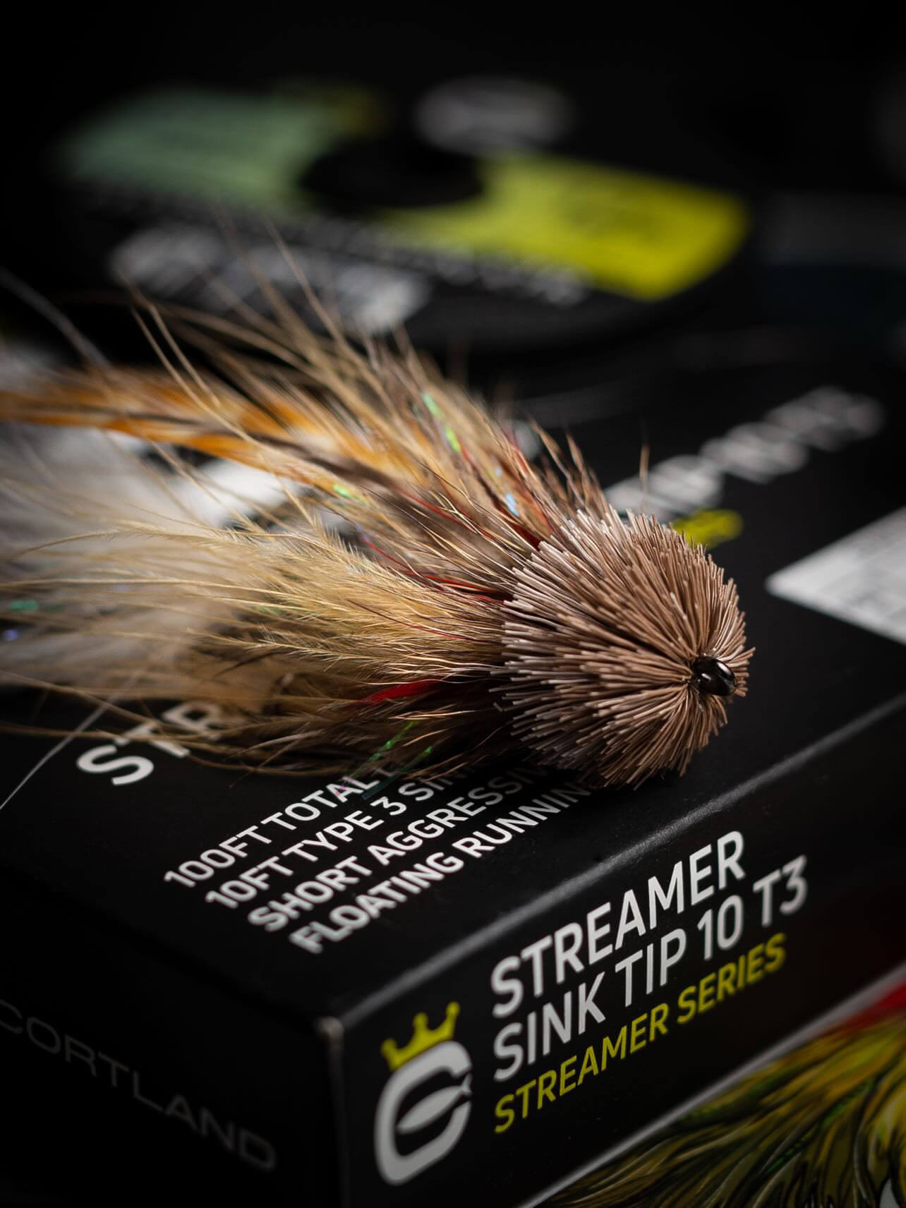Closeup shot of the Streamer Sink Tip 10 T3 box with a fishing fly on top of it 