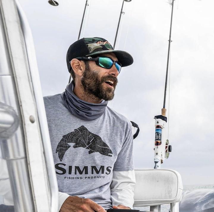Vinny wearing sunglasses, with fly fishing rods behind him